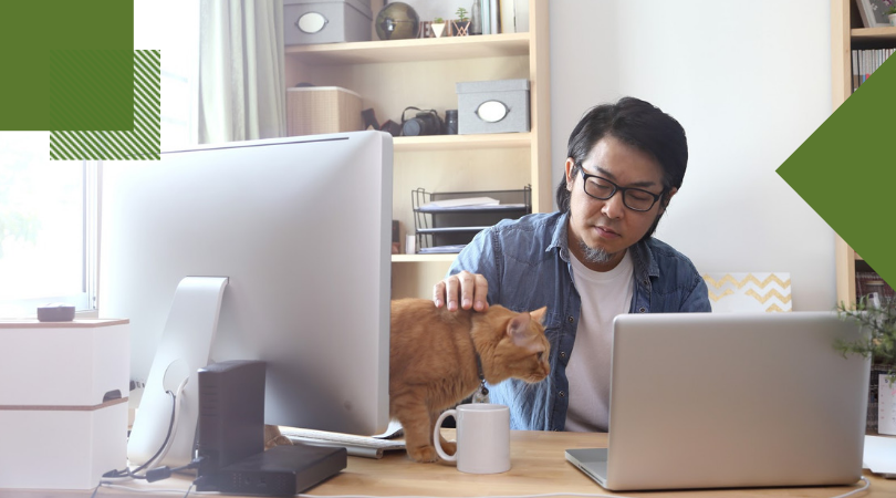 Man petting his cat while working at this desk in his home